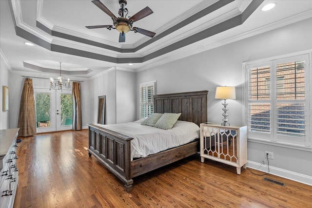 bedroom with ornamental molding, multiple windows, ceiling fan with notable chandelier, and a tray ceiling