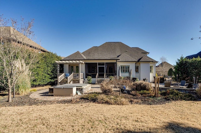 rear view of house with a hot tub and a sunroom