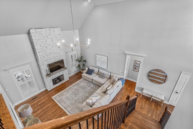 living room with wood-type flooring, high vaulted ceiling, a chandelier, and a fireplace