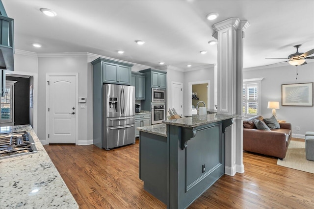 kitchen featuring ornate columns, appliances with stainless steel finishes, ceiling fan, dark hardwood / wood-style flooring, and a kitchen bar