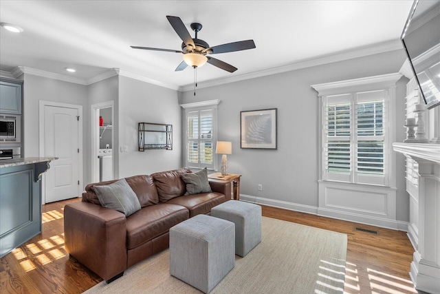 living room featuring ceiling fan, crown molding, a healthy amount of sunlight, and light hardwood / wood-style flooring