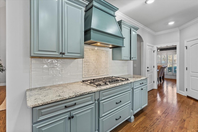 kitchen with custom exhaust hood, stainless steel gas cooktop, ornamental molding, dark hardwood / wood-style floors, and decorative backsplash