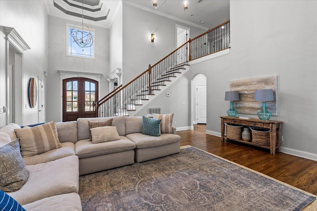 living room featuring dark wood-type flooring, a high ceiling, french doors, an inviting chandelier, and crown molding