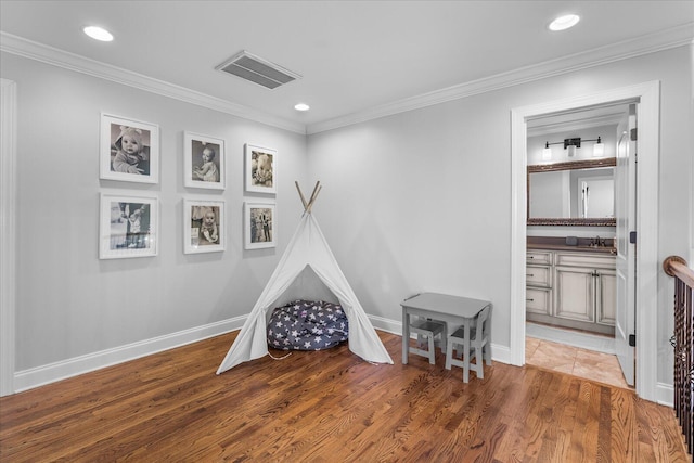 recreation room with ornamental molding, sink, and hardwood / wood-style flooring