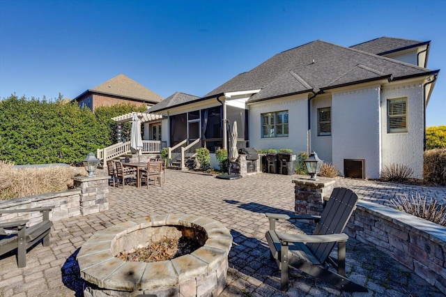 rear view of house featuring an outdoor fire pit, a patio, a sunroom, and a pergola