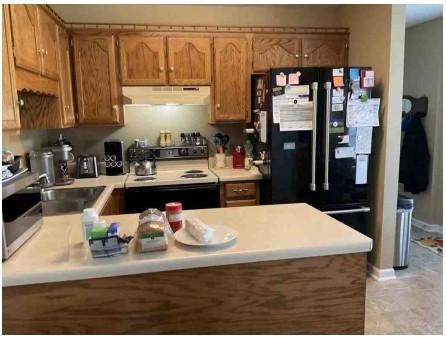 kitchen with black fridge, electric range oven, and kitchen peninsula