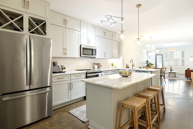 kitchen with light stone countertops, pendant lighting, stainless steel appliances, a kitchen bar, and a kitchen island