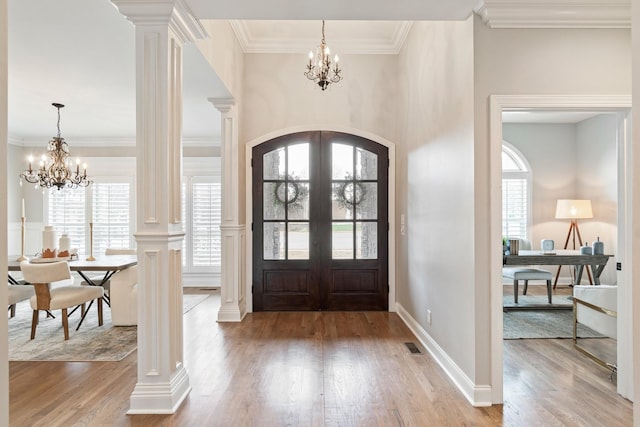 entryway with french doors, plenty of natural light, a chandelier, and ornate columns