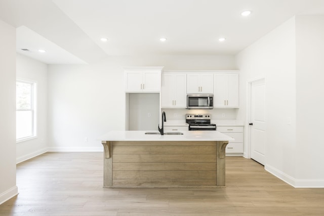 kitchen featuring an island with sink, appliances with stainless steel finishes, white cabinetry, and sink