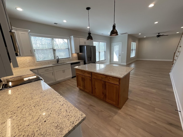 kitchen featuring white cabinets, stainless steel appliances, a center island, and sink