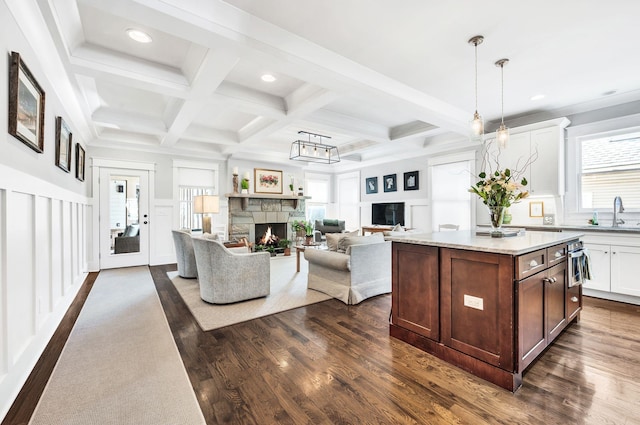 kitchen featuring coffered ceiling, pendant lighting, dark wood-type flooring, a kitchen island, and a fireplace