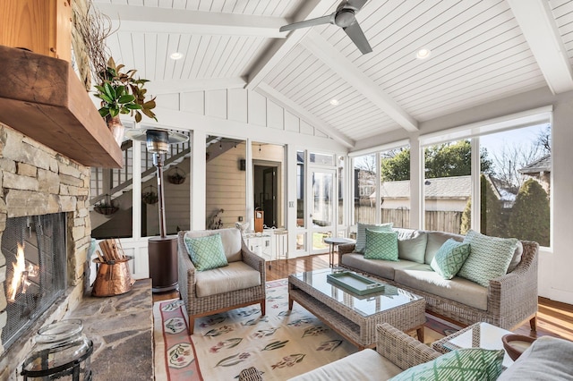 sunroom featuring a fireplace, ceiling fan, lofted ceiling with beams, and wood ceiling