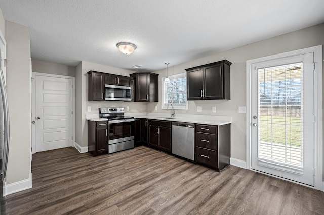 kitchen featuring hardwood / wood-style floors, stainless steel appliances, dark brown cabinetry, sink, and decorative light fixtures