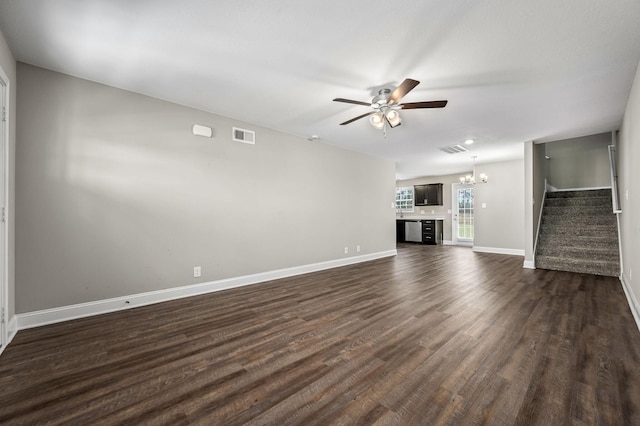 unfurnished living room featuring ceiling fan with notable chandelier and dark wood-type flooring