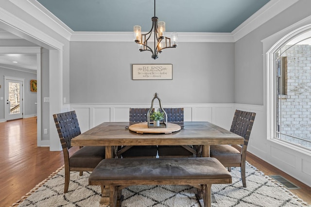 dining room with a chandelier, ornamental molding, and hardwood / wood-style flooring