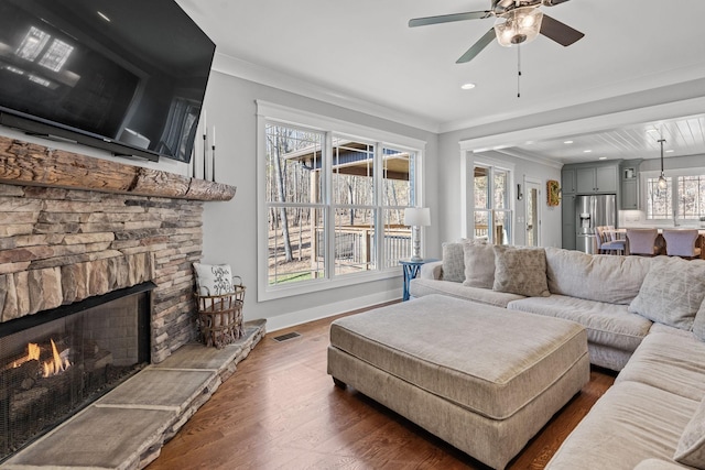 living room featuring ceiling fan, dark hardwood / wood-style flooring, a wealth of natural light, and a fireplace