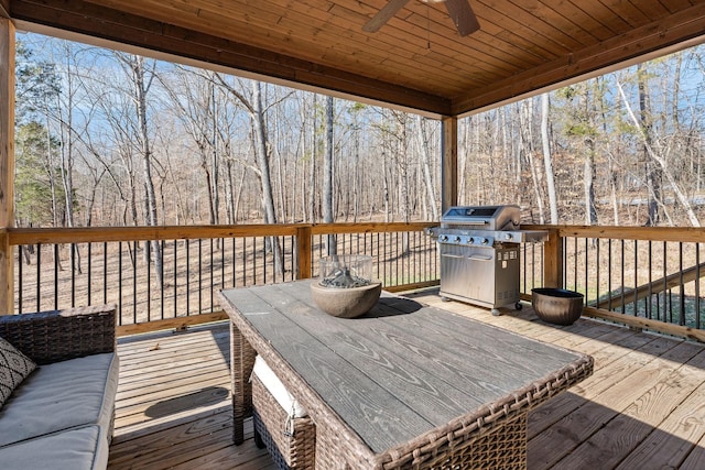 wooden deck with ceiling fan and area for grilling