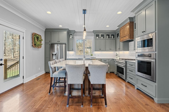 kitchen with a kitchen breakfast bar, appliances with stainless steel finishes, hanging light fixtures, a center island, and tasteful backsplash