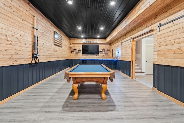 game room with wood walls, a barn door, light hardwood / wood-style floors, and billiards