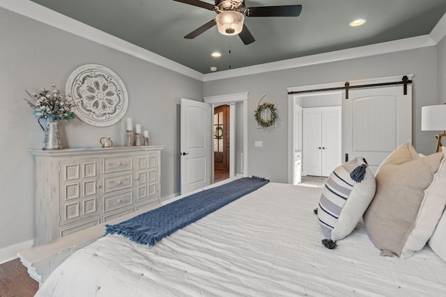 bedroom with ornamental molding, ceiling fan, light wood-type flooring, and a barn door