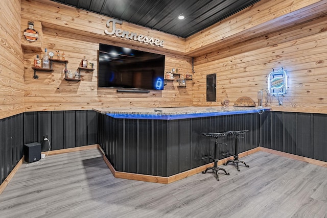 bar featuring wooden walls and light hardwood / wood-style floors