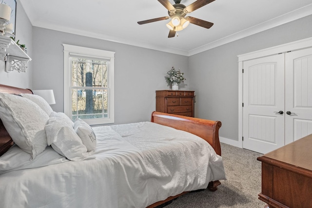 carpeted bedroom with ceiling fan, ornamental molding, and a closet