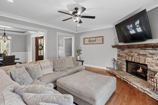 living room featuring ceiling fan with notable chandelier, a fireplace, ornamental molding, and hardwood / wood-style floors