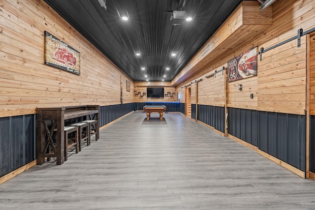 playroom with pool table, wood walls, light hardwood / wood-style floors, and a barn door