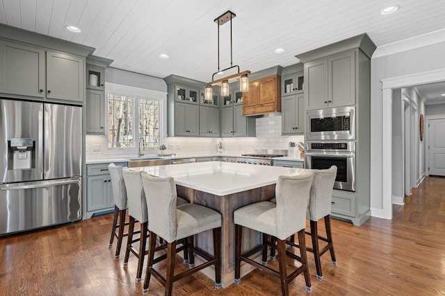 kitchen with pendant lighting, a center island, a kitchen bar, dark hardwood / wood-style flooring, and appliances with stainless steel finishes