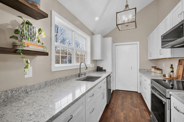 kitchen with appliances with stainless steel finishes, light stone countertops, sink, white cabinetry, and decorative light fixtures