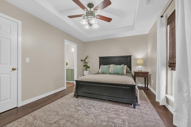 bedroom featuring ceiling fan, dark hardwood / wood-style flooring, connected bathroom, and a raised ceiling