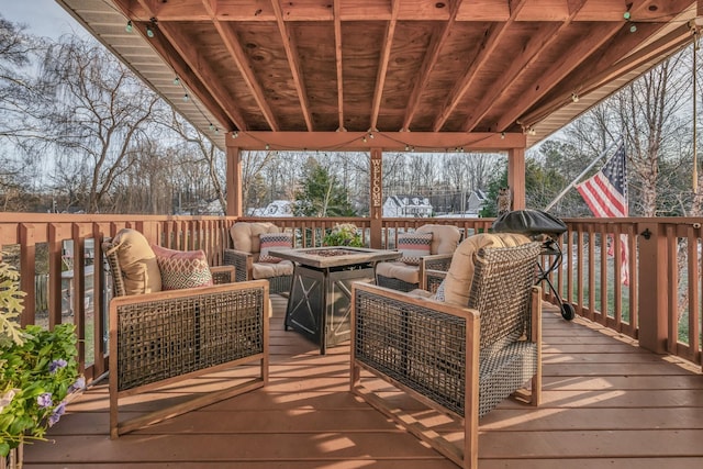 wooden deck featuring an outdoor living space with a fire pit