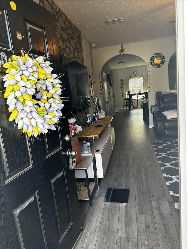 hallway with a textured ceiling and dark hardwood / wood-style flooring