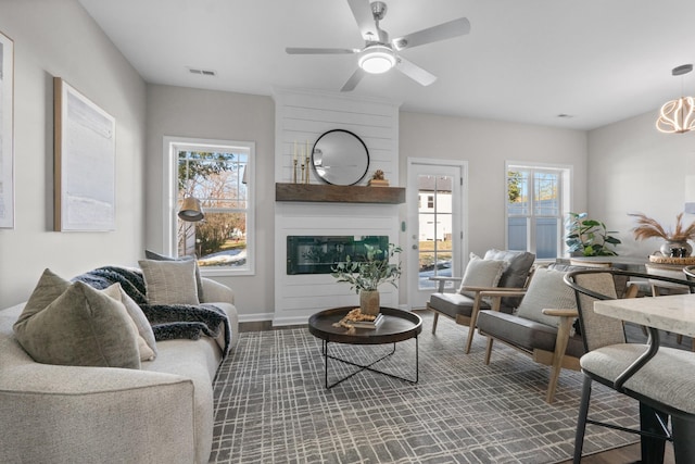 living room with ceiling fan and a large fireplace