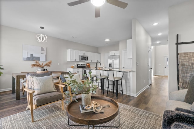 living room with dark wood-type flooring, sink, and ceiling fan