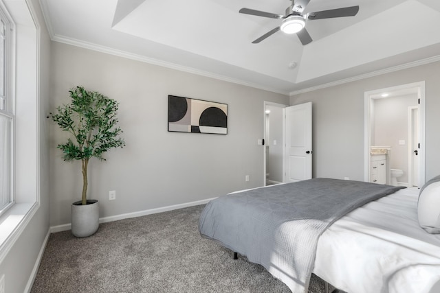 bedroom with a raised ceiling, ceiling fan, light colored carpet, ensuite bathroom, and crown molding