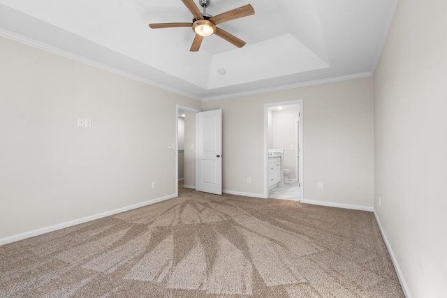 unfurnished bedroom with ensuite bathroom, light colored carpet, ceiling fan, crown molding, and a tray ceiling