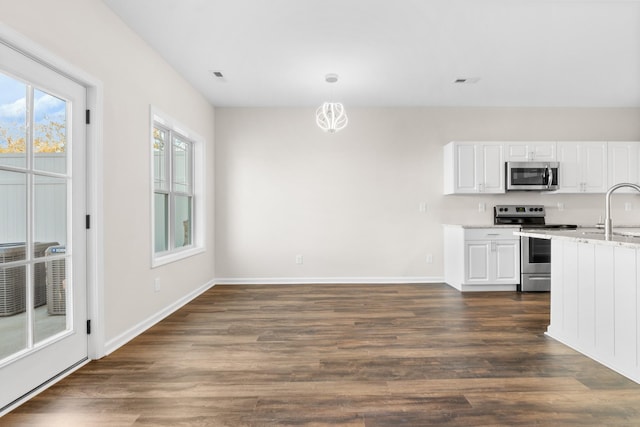 kitchen with pendant lighting, appliances with stainless steel finishes, dark wood-type flooring, white cabinetry, and sink