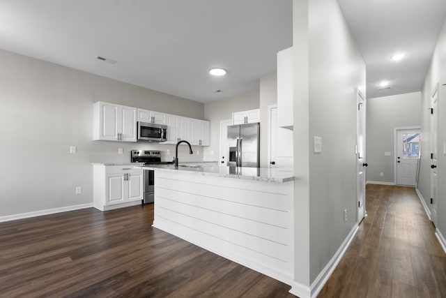 kitchen featuring appliances with stainless steel finishes, dark hardwood / wood-style flooring, light stone countertops, white cabinets, and sink