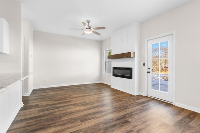 unfurnished living room with ceiling fan, dark hardwood / wood-style flooring, heating unit, and a large fireplace