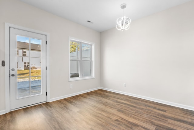 unfurnished dining area with dark wood-type flooring and a chandelier