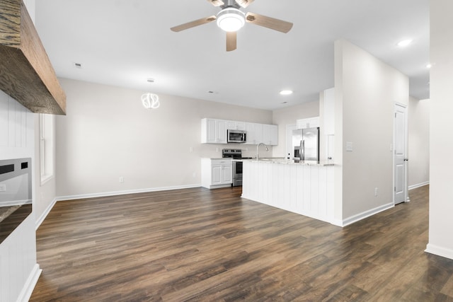 kitchen with white cabinets, appliances with stainless steel finishes, dark hardwood / wood-style flooring, kitchen peninsula, and ceiling fan