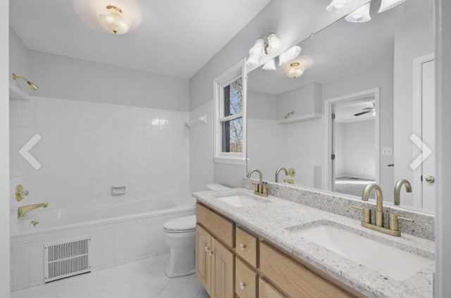 full bathroom with toilet, tiled shower / bath combo, ceiling fan, and vanity