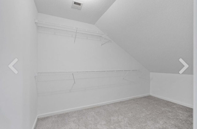 walk in closet with vaulted ceiling and carpet flooring