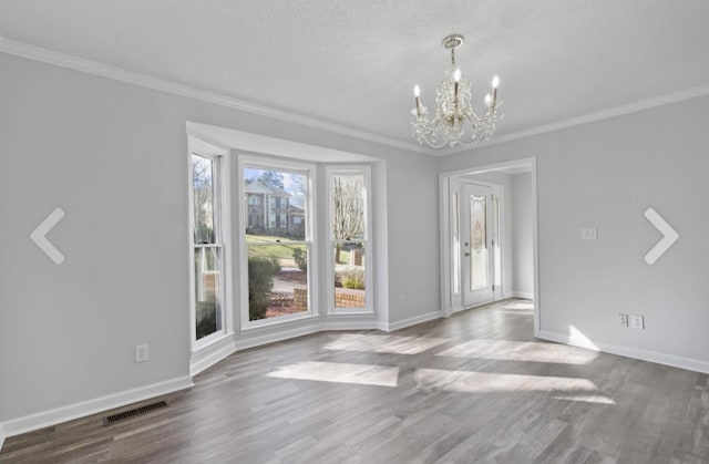 unfurnished dining area with a textured ceiling, hardwood / wood-style floors, crown molding, and a chandelier