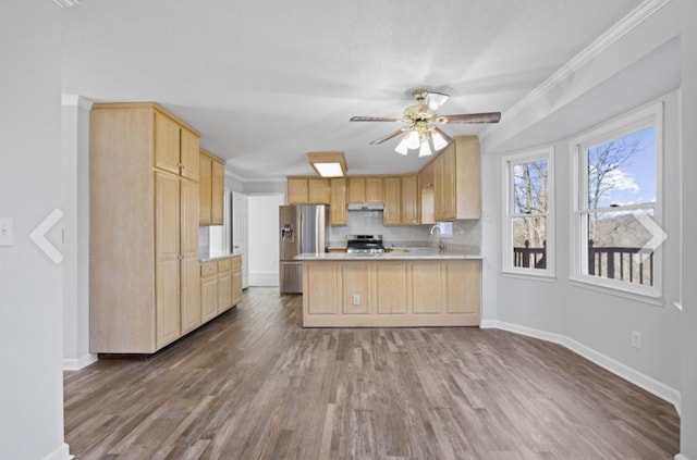 kitchen featuring stainless steel appliances, light brown cabinets, decorative backsplash, and kitchen peninsula