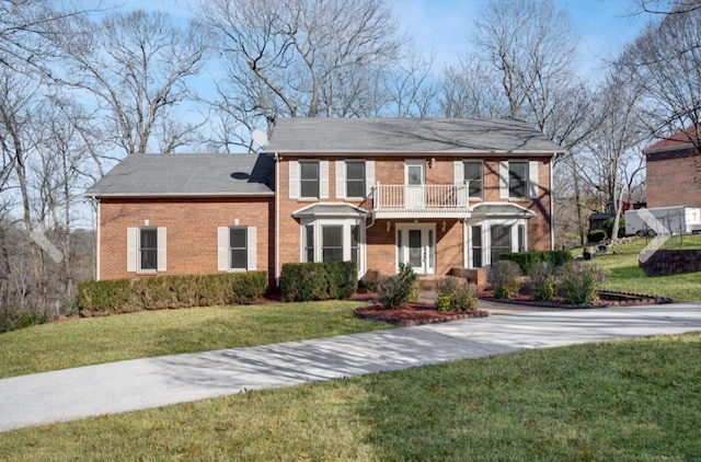 colonial home with a balcony and a front yard