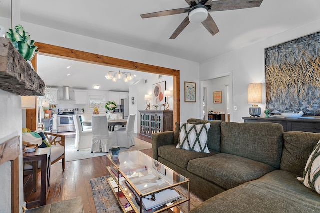 living room featuring ceiling fan with notable chandelier and wood-type flooring