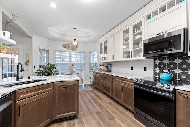 kitchen featuring hardwood / wood-style flooring, a raised ceiling, white cabinetry, appliances with stainless steel finishes, and sink