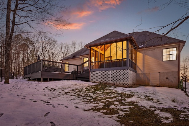 snow covered house featuring a deck and a sunroom